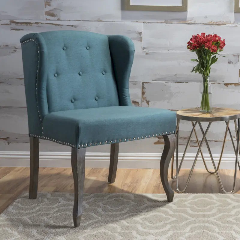Sillón decorativo de una plaza con respaldo alto, color verde azulado, con botones capitoné y estructura de madera de caucho