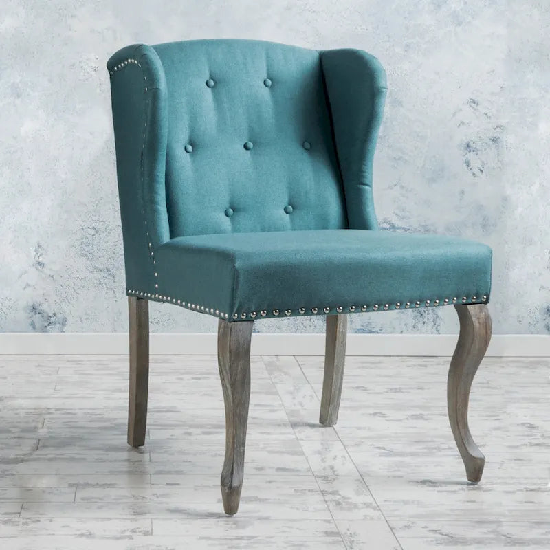 Sillón decorativo de una plaza con respaldo alto, color verde azulado, con botones capitoné y estructura de madera de caucho